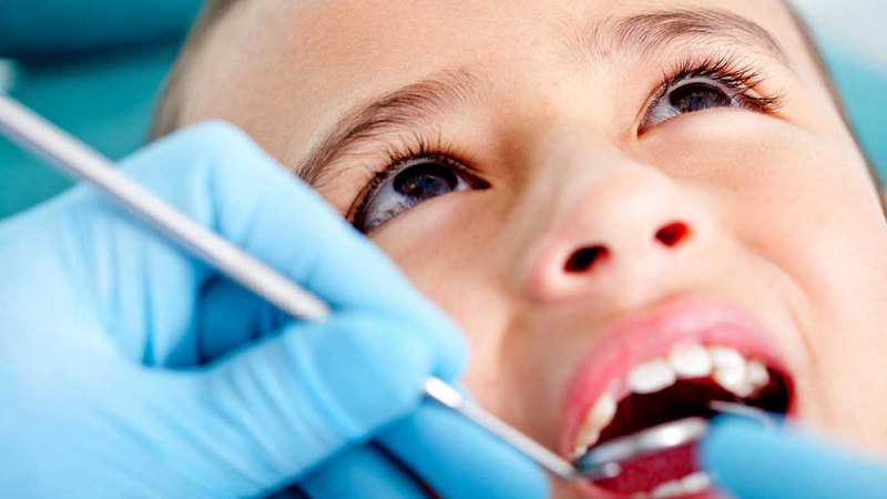  Image of a child tooth extraction procedure; Child at a pediatric dentist is getting his teeth examined